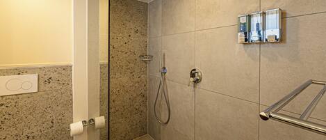 A modern bathroom with a glass shower enclosure, a toilet, and a towel rack.