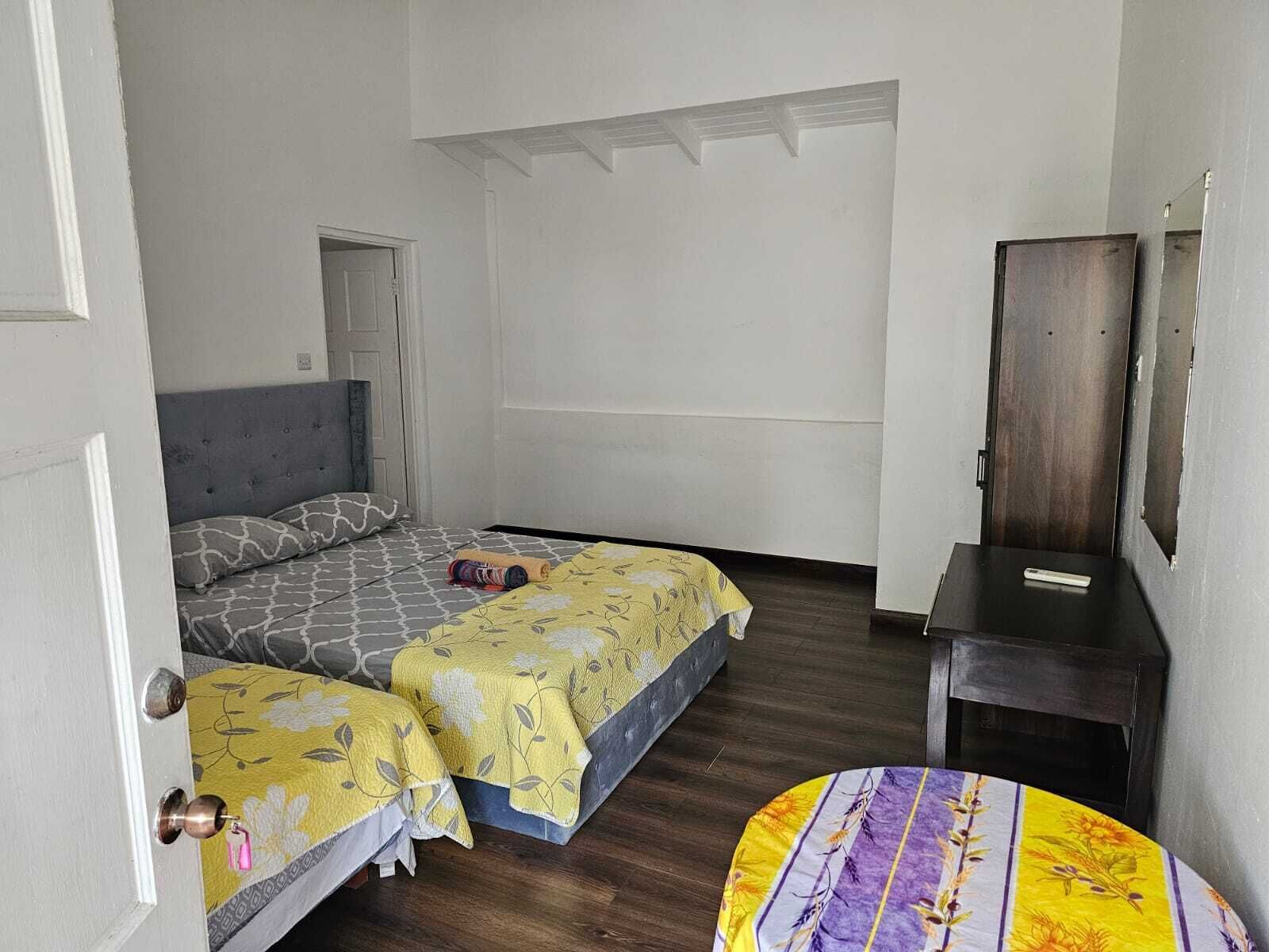 Une chambre avec deux lits, un plancher en bois, une porte et une petite table avec un miroir.