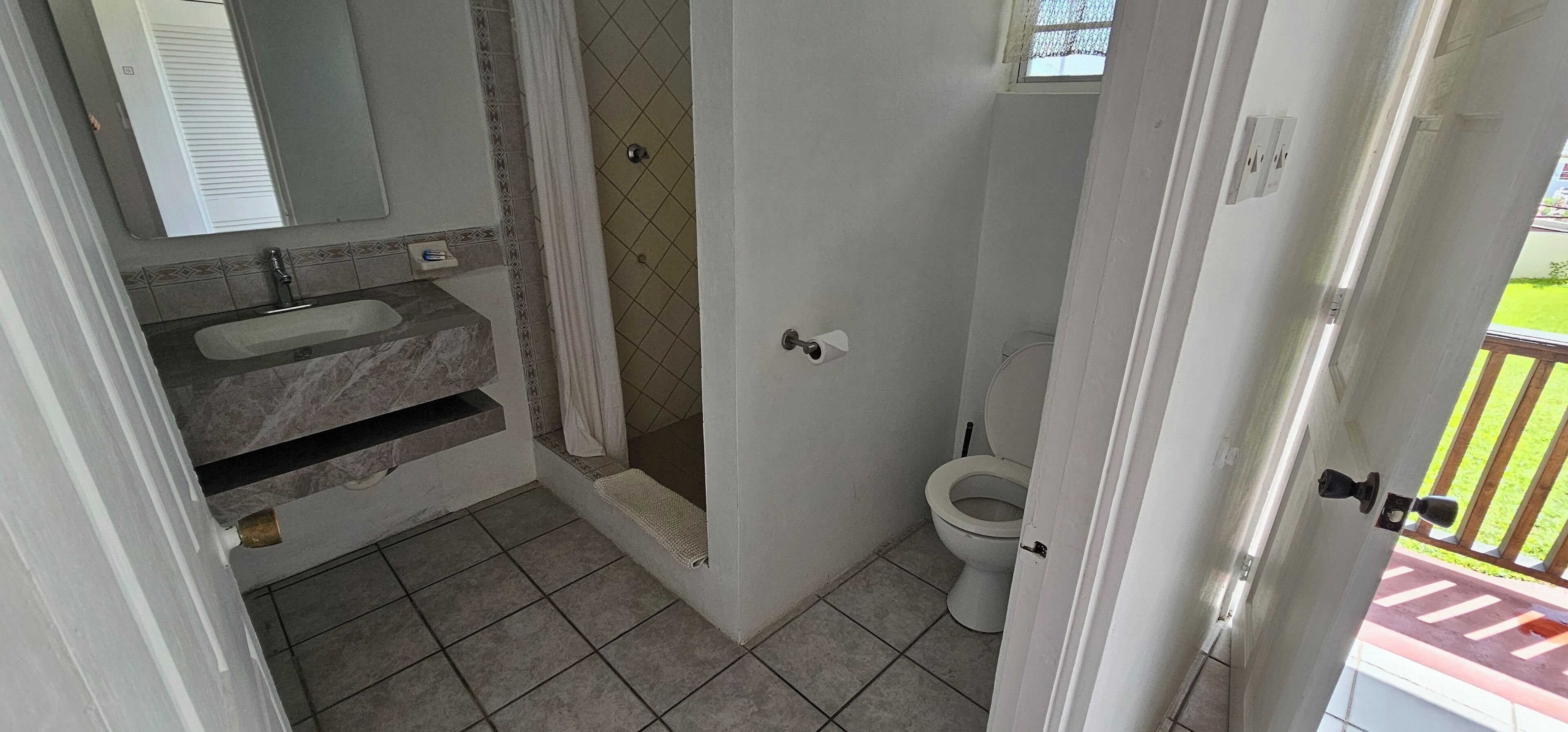Un baño con lavamanos de mármol, ducha y retrete.