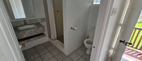 Un baño con lavamanos de mármol, ducha y retrete.