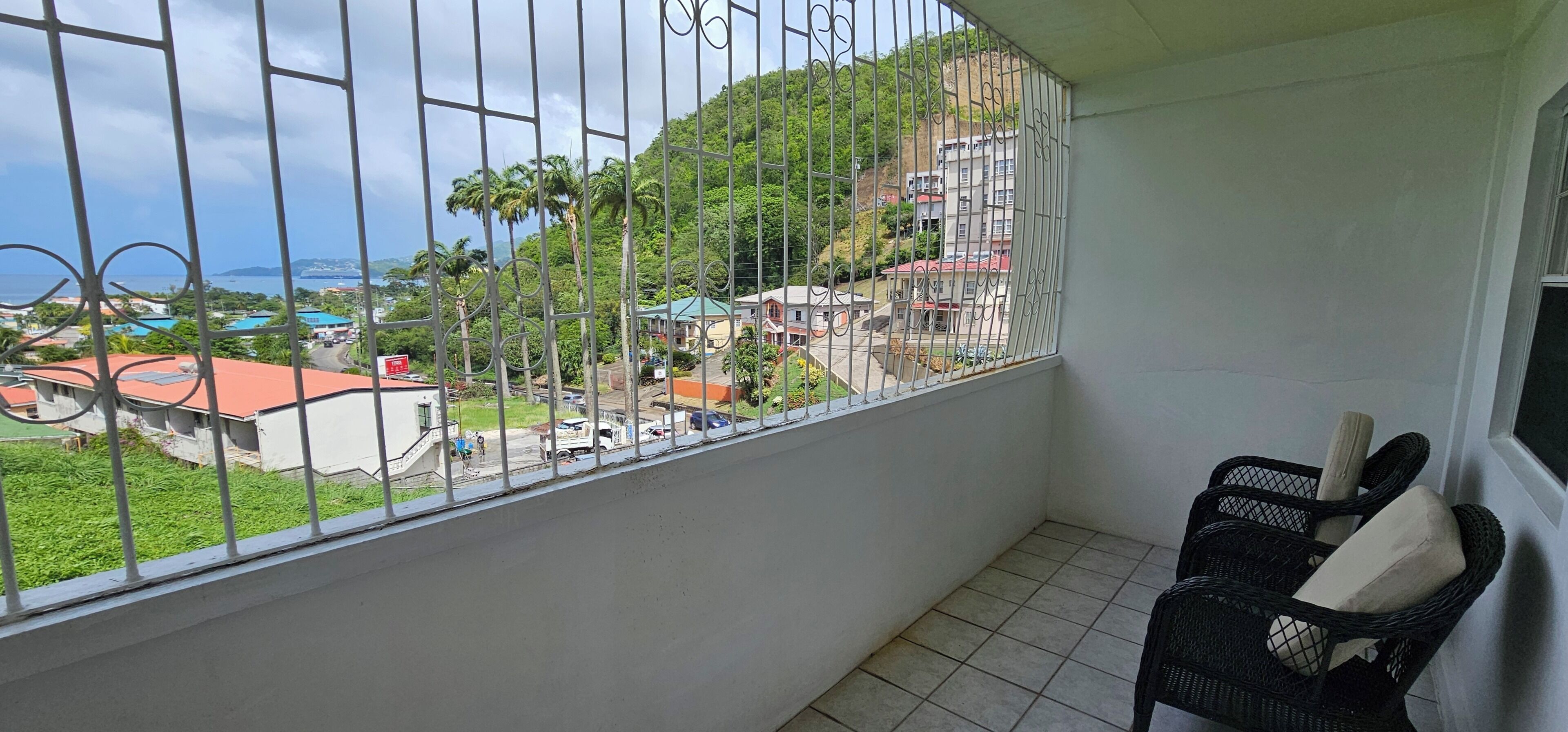 Un balcone con vista su una collina, una sedia e un cesto.