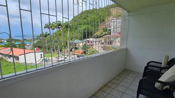 Un balcone con vista su una collina, una sedia e un cesto.
