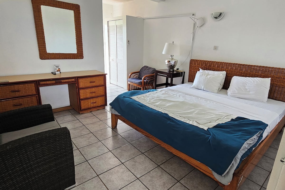 A hotel room with a bed, a desk, a chair, a TV, and a wardrobe.