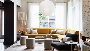 A modern living room with a yellow sofa, round ottomans, a small table, and a fireplace. - The Laurel Inn, part of JdV by Hyatt (San Francisco)