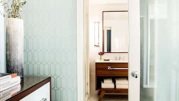 A bathroom with a wooden vanity, a mirror, and a vase with flowers.