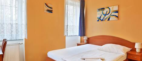A neatly made bed with white linens, a wooden headboard, and a bedside table with a lamp.