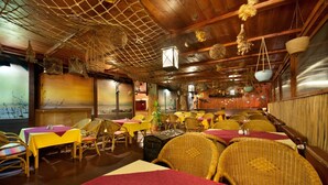 Un restaurante con techos de madera, muebles de mimbre y un mural con motivos marinos.