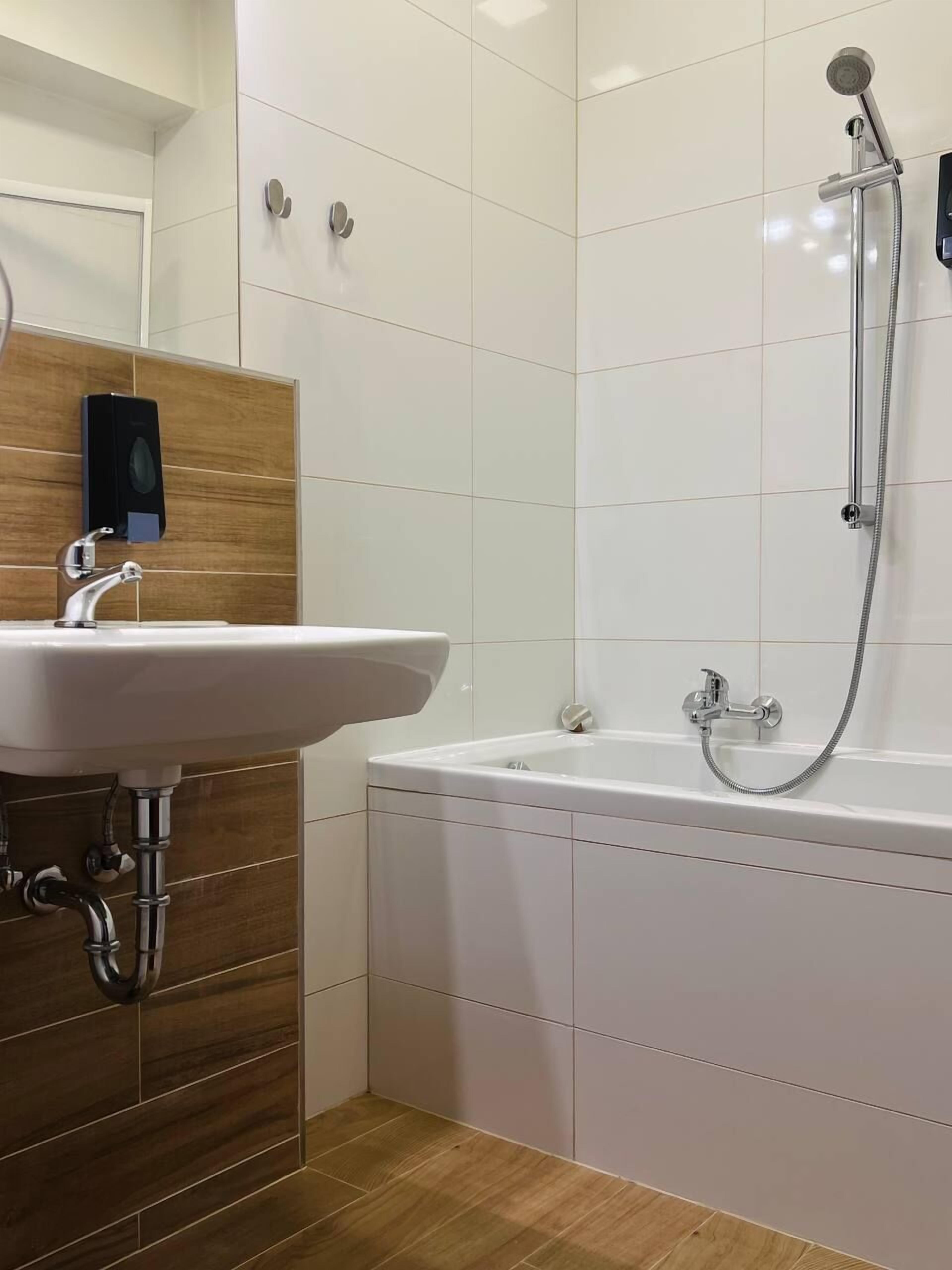 A bathroom with a white sink, a bathtub, and a shower.
