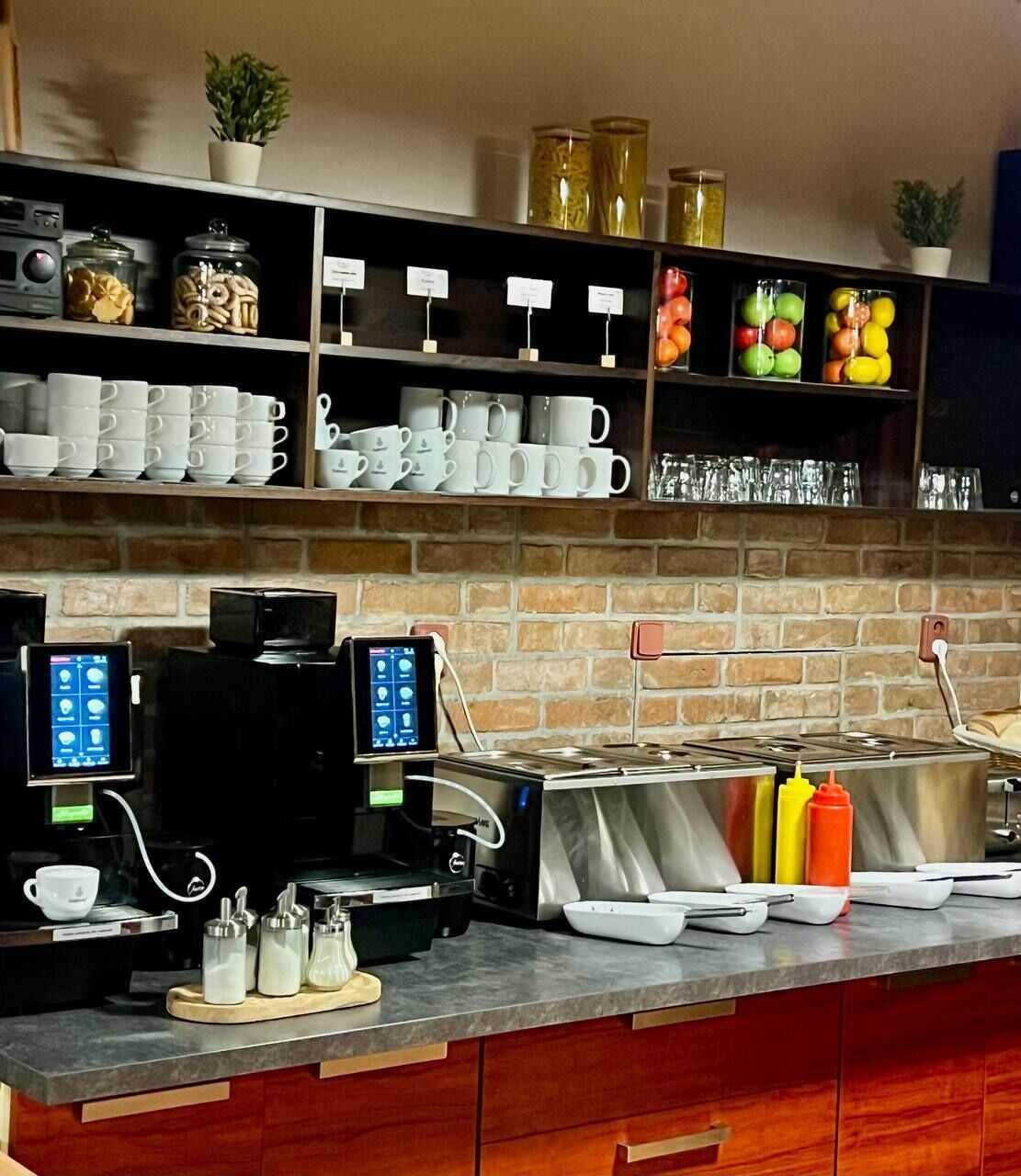 Una zona de cafè amb diverses màquines de cafè, una varietat de tasses i dispensadors de condiments.