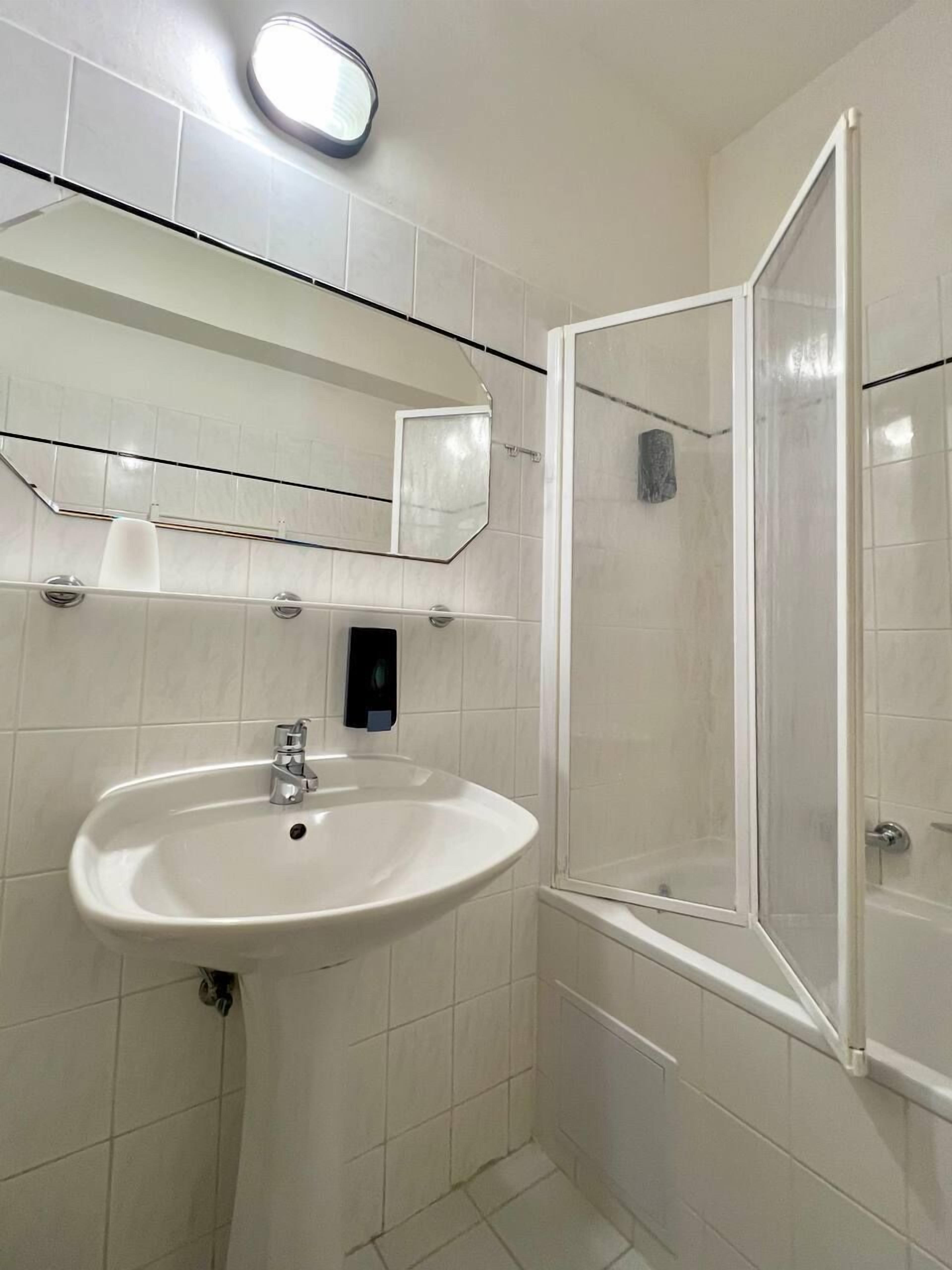Een badkamer met een wastafel, spiegel en douche.