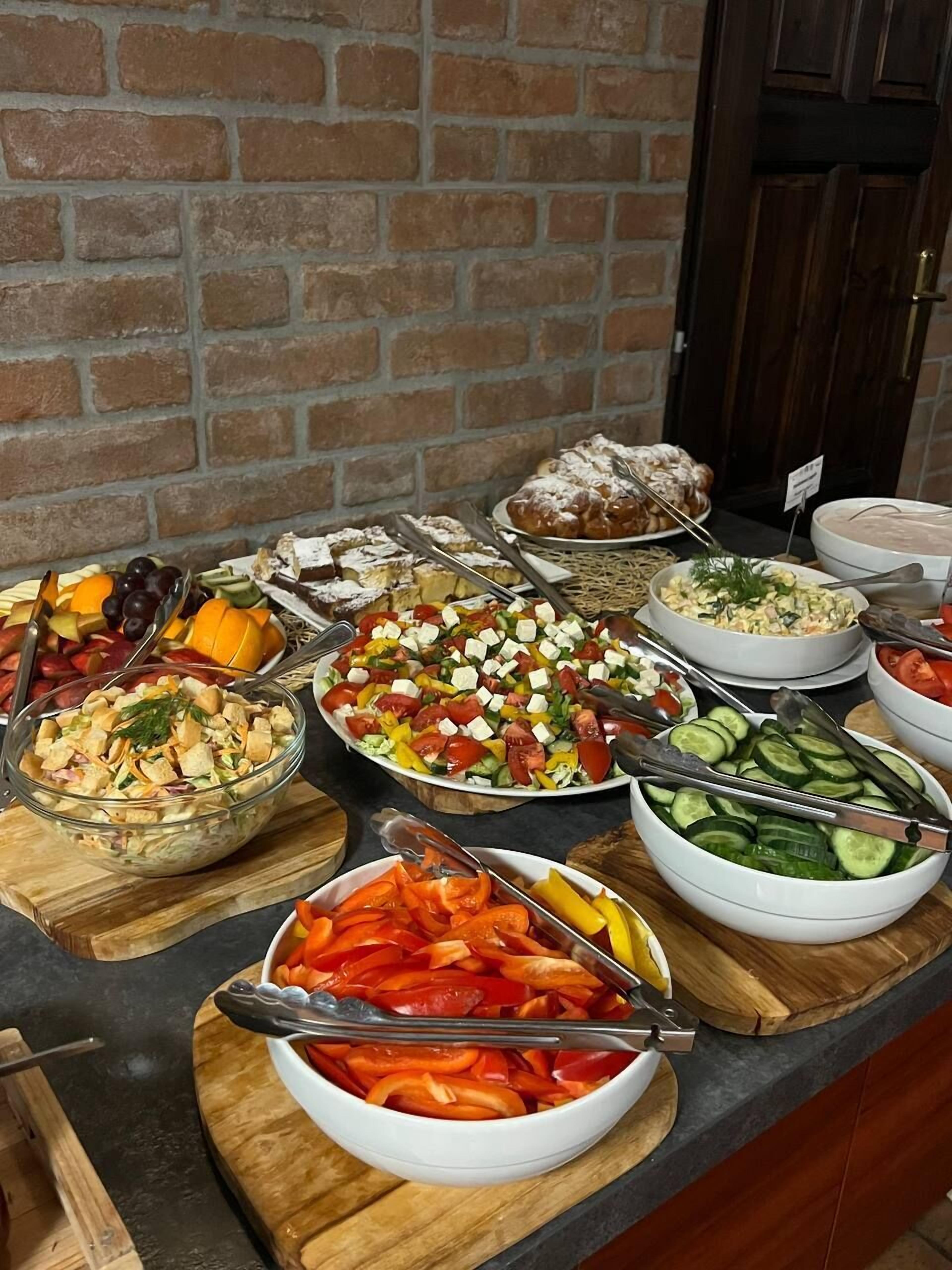 A buffet with various dishes including salads, fruits, and bread.