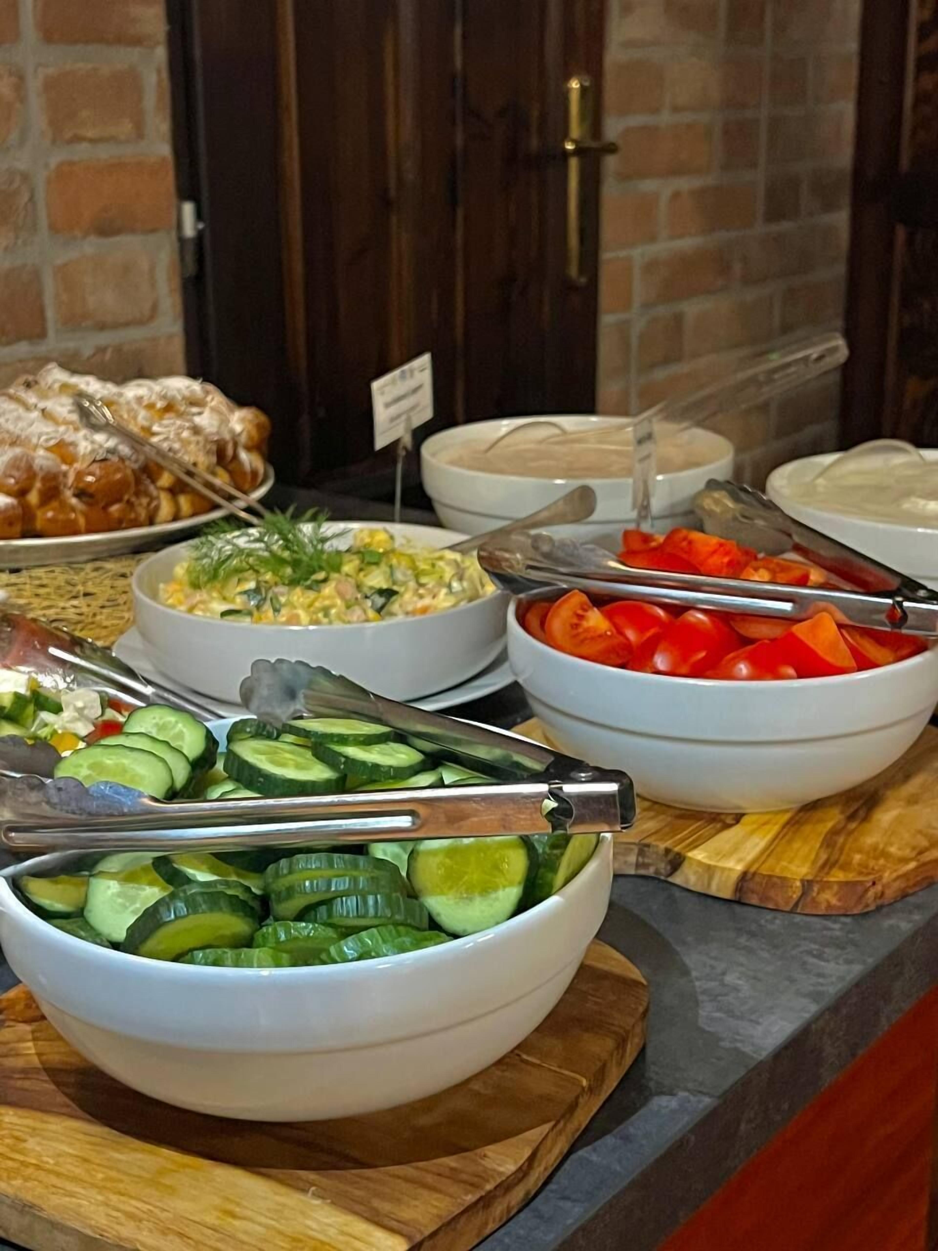 Ein Buffet mit verschiedenen Speisen, darunter ein Salat, Gurkenscheiben und eine Schale mit roten Paprika.