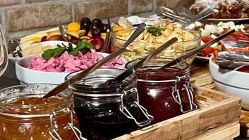 Uma bandeja de madeira com diversos alimentos e potes de compotas em uma bancada.