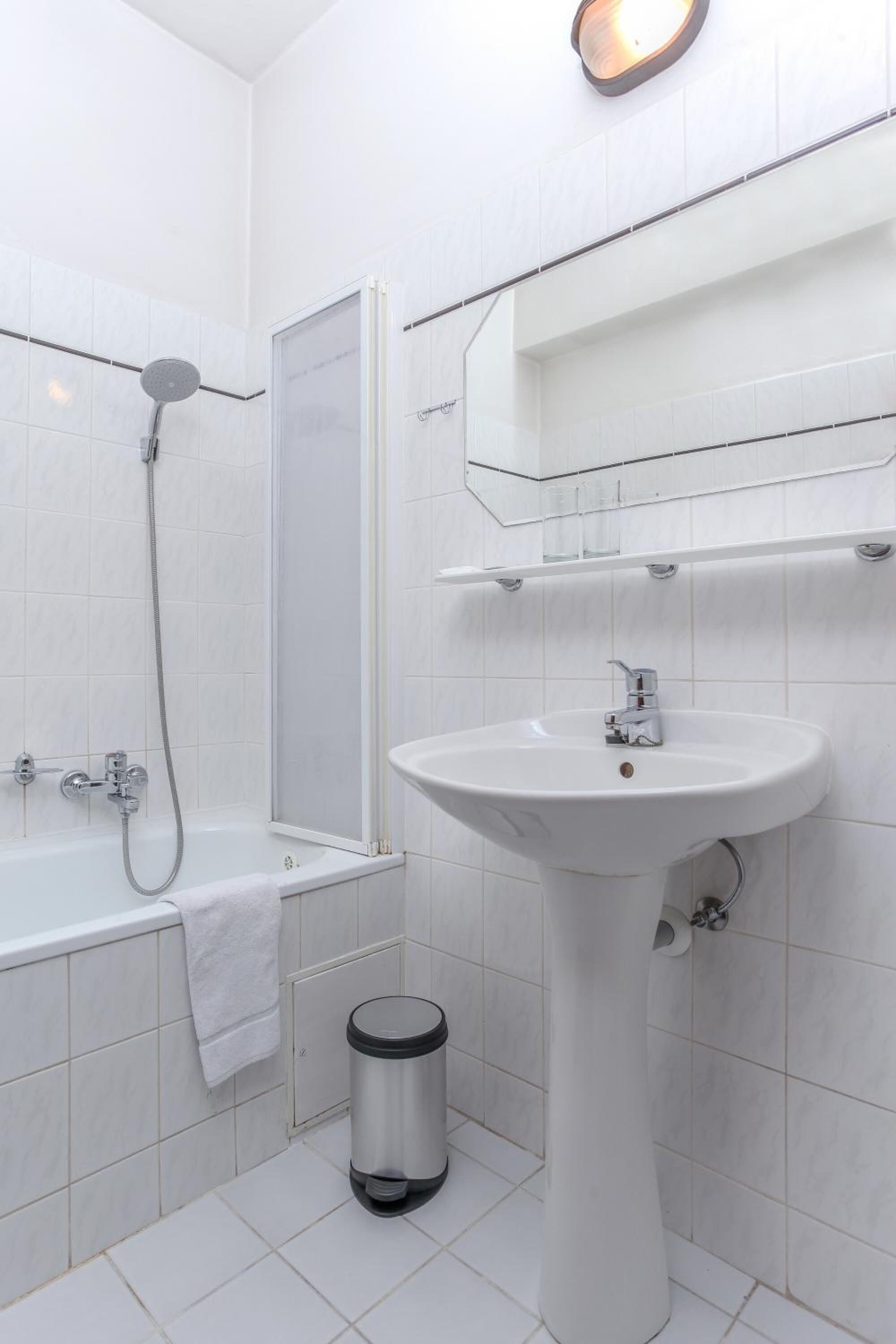A modern bathroom with a white sink, a shower, and a toilet.