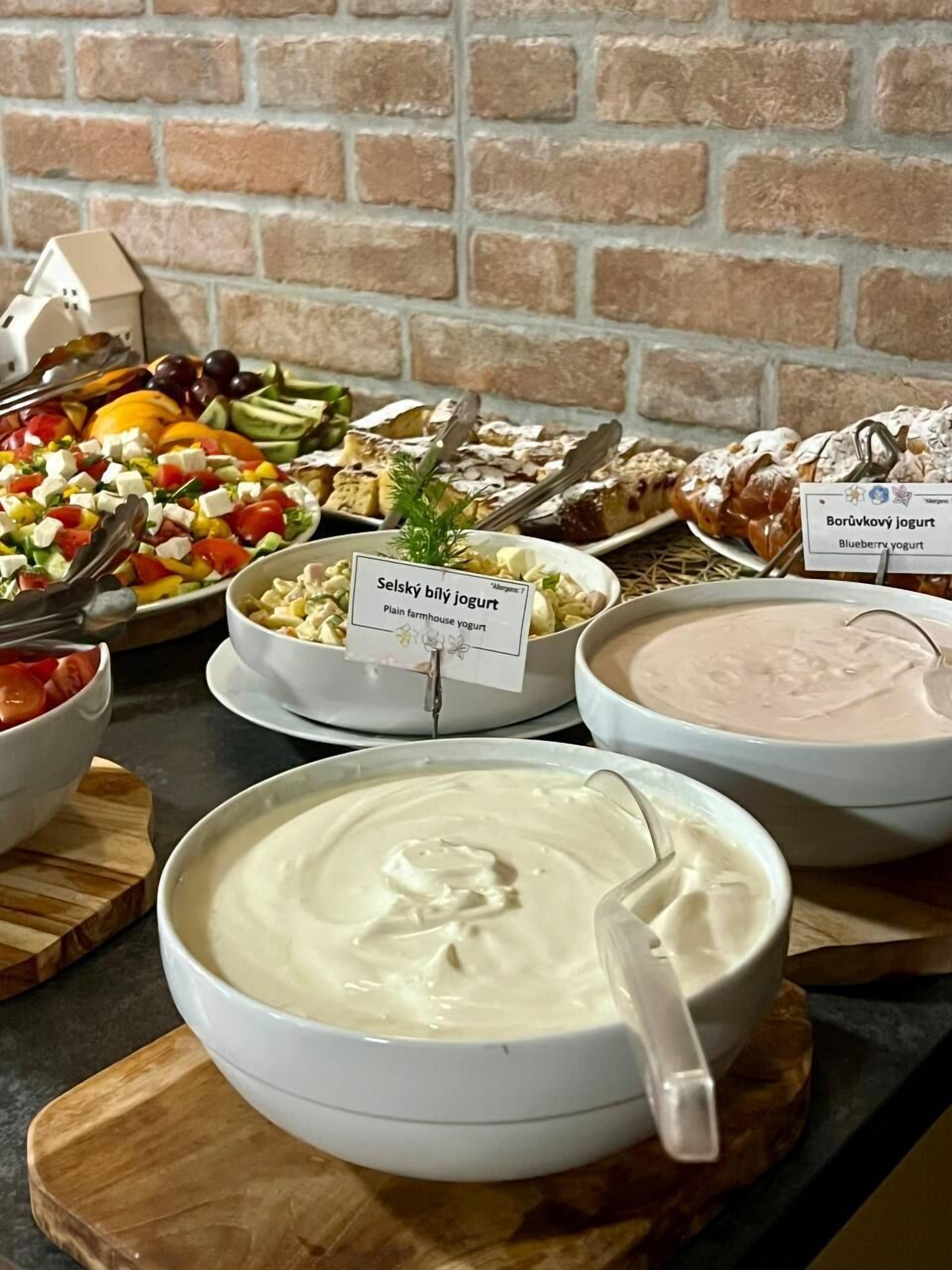 Un bufé con diferentes opciones de comida, incluyendo recipientes con yogur de leche, yogur de arándanos y otros platos.