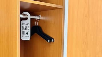 Un armario de madera con una barra para colgar y un cartel que dice 'POR FAVOR, HAGA LA CAMA'.