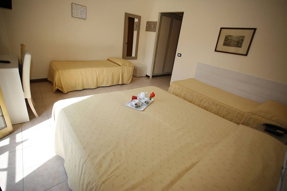 A hotel room with two beds, a desk, and a chair.