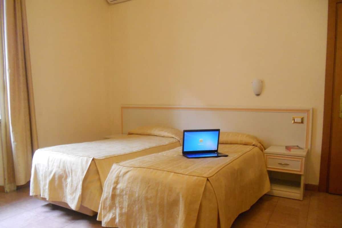 A double bed with a laptop on it, a bedside table, and a nightstand.