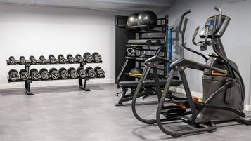 A gym with exercise equipment, including dumbbells, kettlebells, and a treadmill.