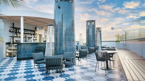 A rooftop bar with a blue and white tiled floor, modern seating, and a bar area with shelves of bottles. - Barceló Santa Cruz Contemporáneo (Santa Cruz de Tenerife)