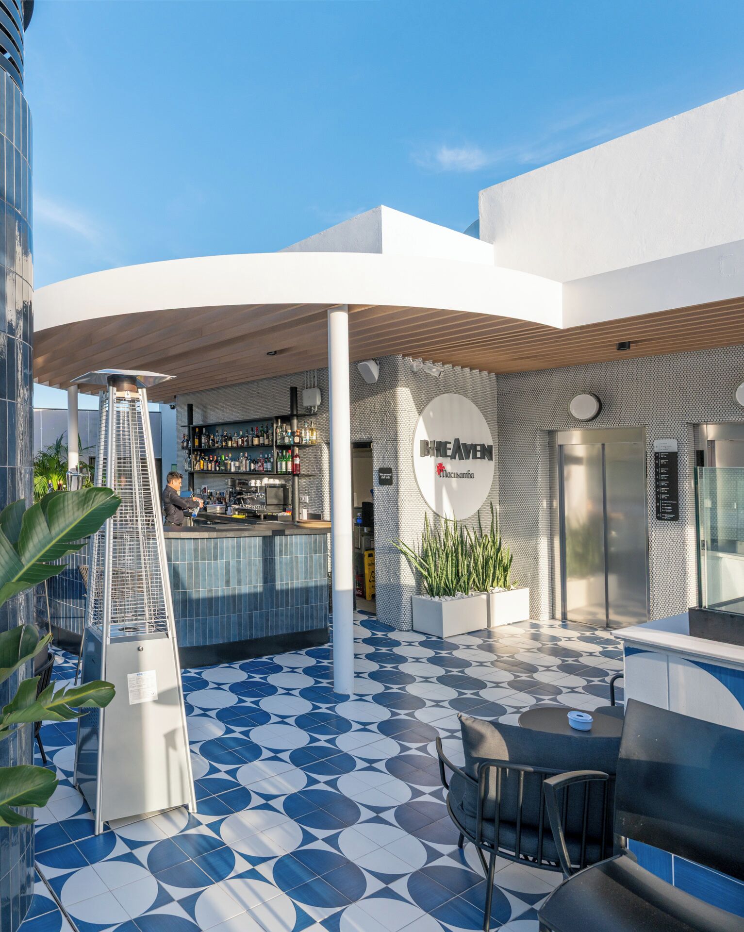 Un espace bar extérieur au design moderne, doté d’un sol à motifs, de sièges et d’un comptoir.