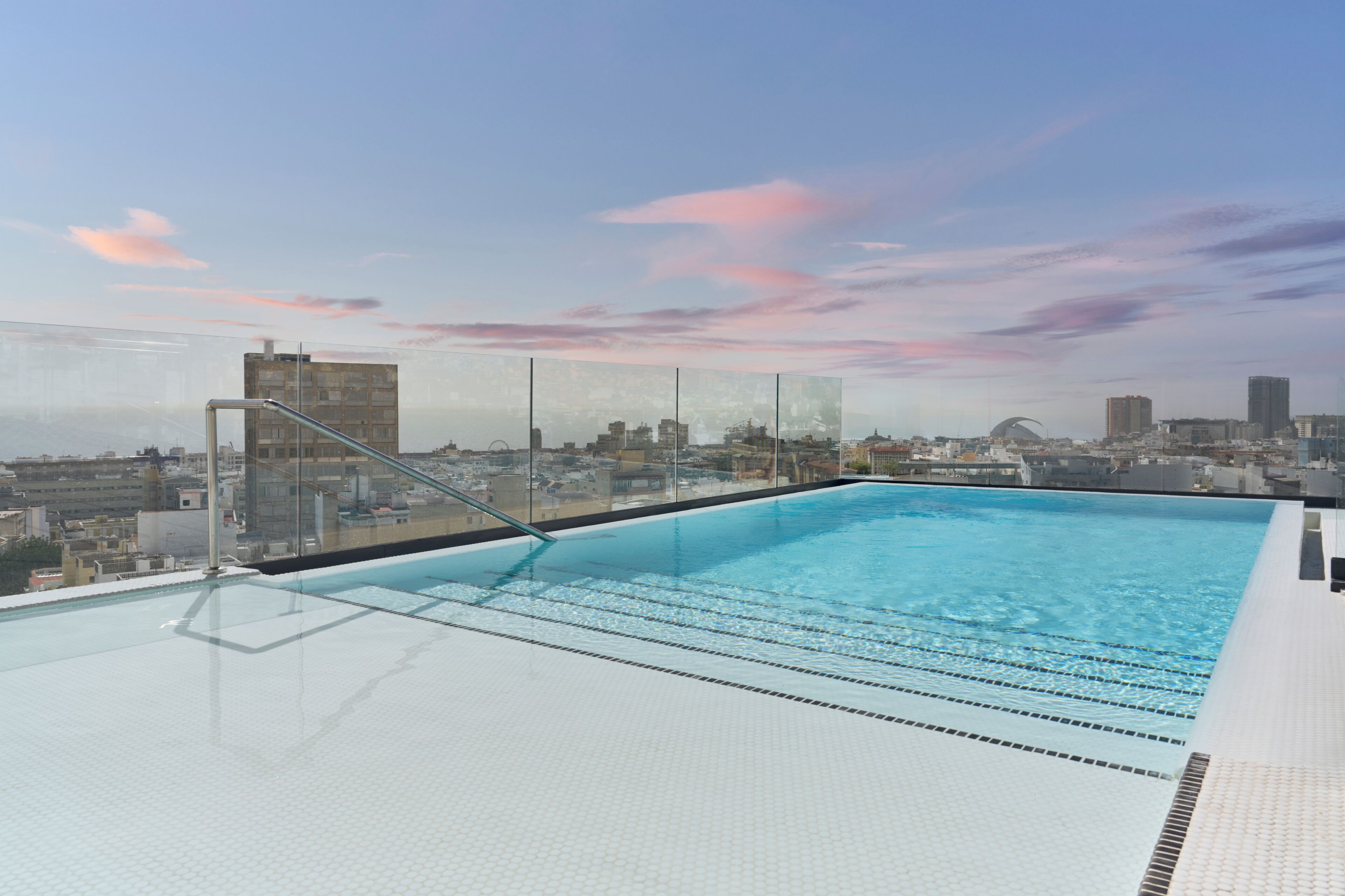 Una piscina en la azotea con agua azul cristalina, rodeada de vistas a la ciudad.