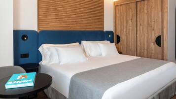 Una habitación de hotel con una cama, una mesa redonda con un libro y un cabecero de madera.