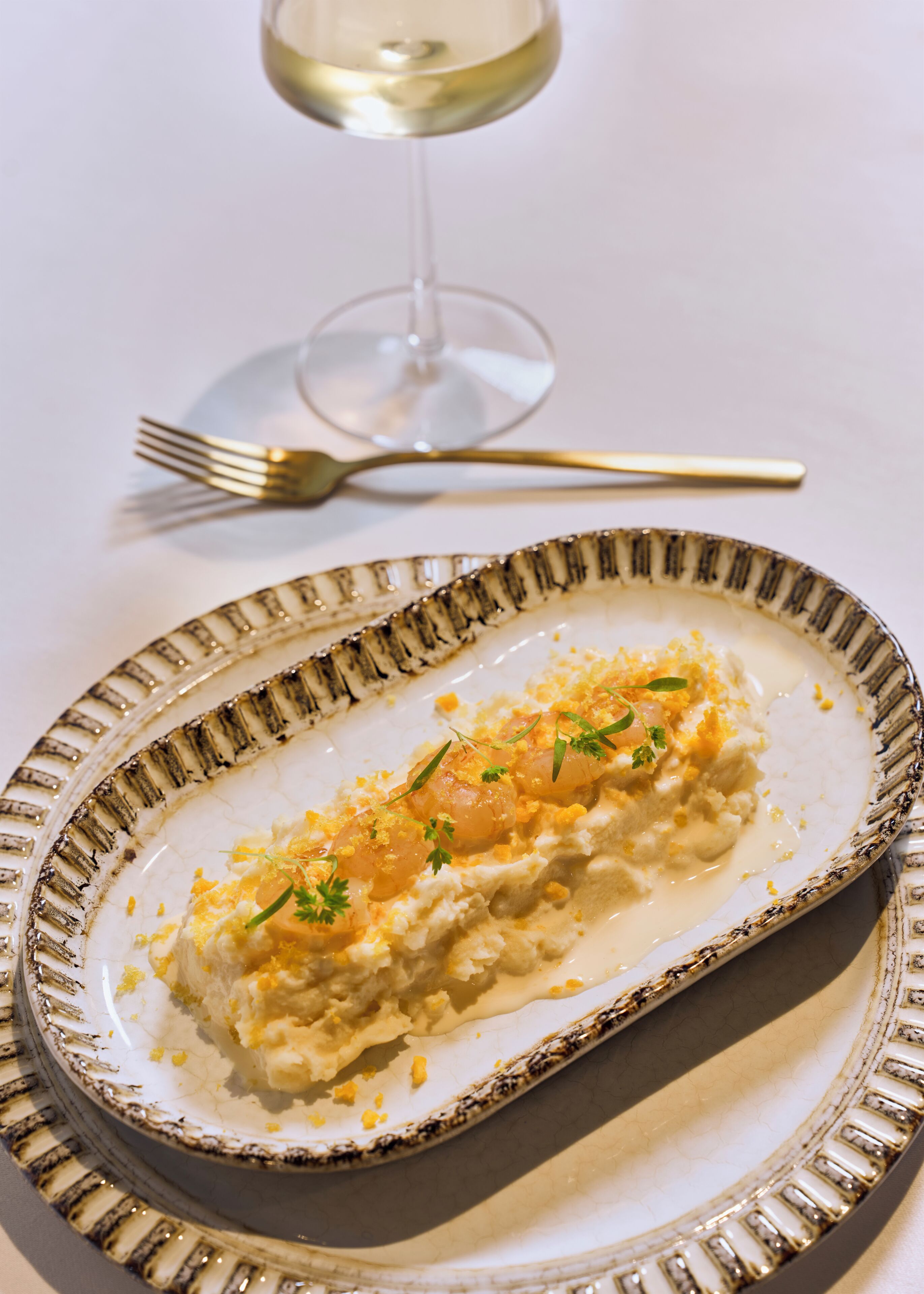 Un plato con base cremosa, decorado con hierbas y ralladura de limón.