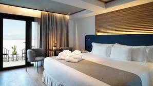 A modern hotel room with a large bed, a seating area with chairs, a small table with a plant, and a view through a glass door. - Barceló Santa Cruz Contemporáneo (Santa Cruz de Tenerife)