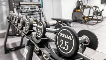 A row of ZIVA 25kg dumbbells on a rack in a gym.