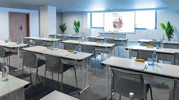 Un salón de conferencias con mesas, sillas y pantallas para presentaciones.