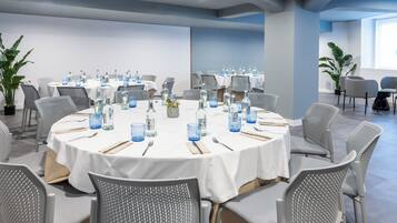 Une salle de conférence équipée de tables rondes, de chaises et de bouteilles d’eau.