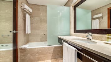 Un baño moderno con cabina de ducha de vidrio, bañera y tocador con lavamanos y espejo.