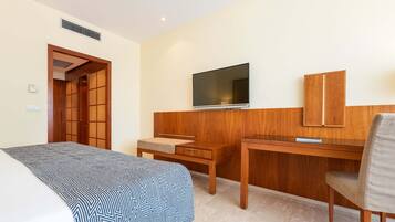Une chambre d’hôtel équipée d’un lit, d’un bureau, d’une chaise, d’une télévision et d’une armoire.