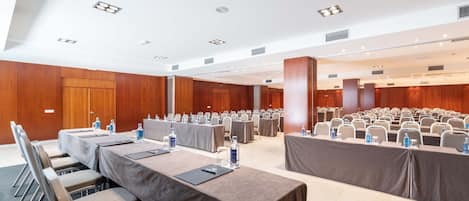 A conference room with multiple tables, chairs, and a stage area.