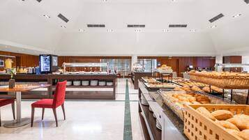 Un moderno buffet con diverse postazioni, tra cui una varietà di pani e pasticceria.