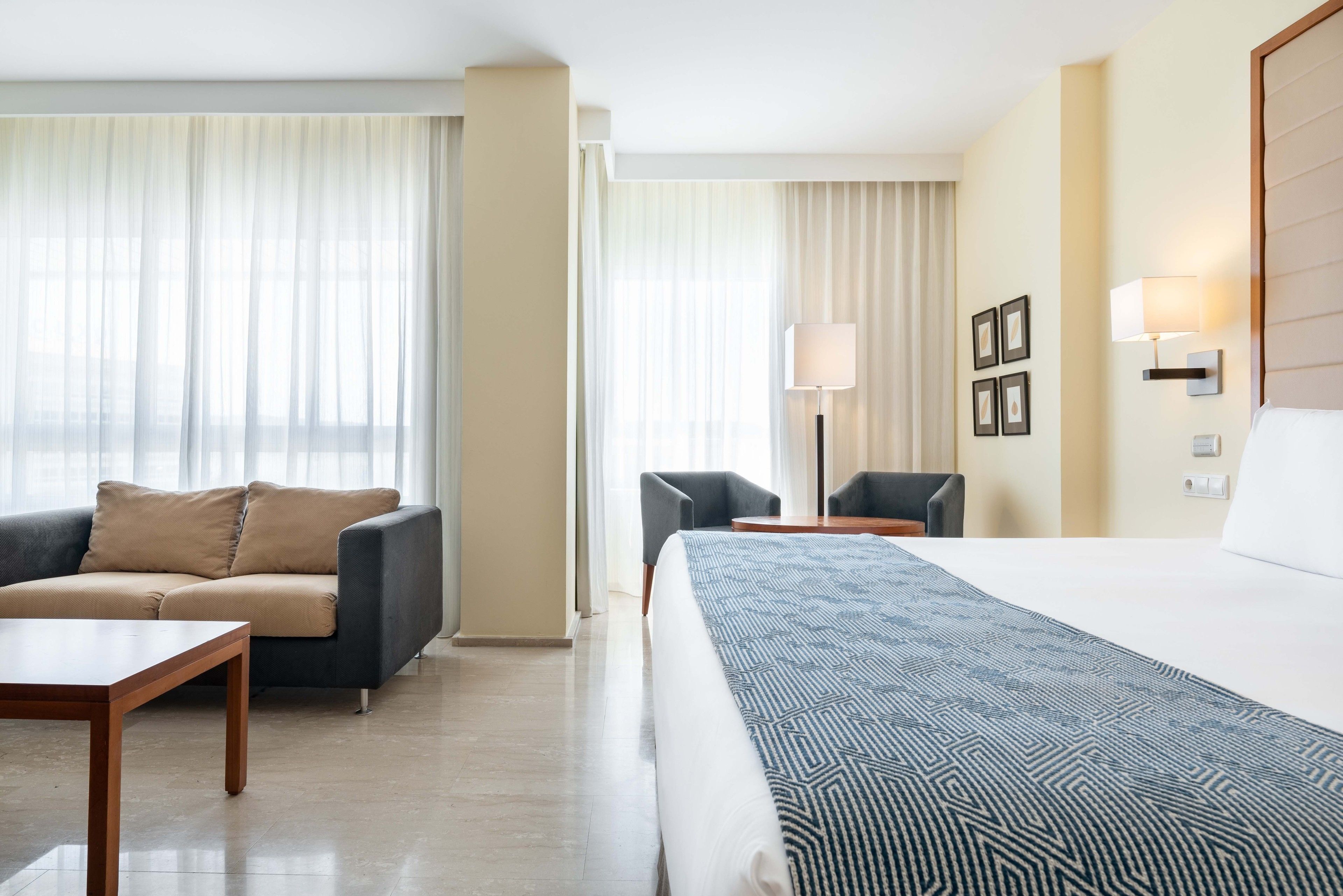 Een hotelkamer met een bed, een bank, een tafel en een stoel.