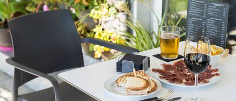 A table with a sandwich, a glass of beer, and a glass of red wine.