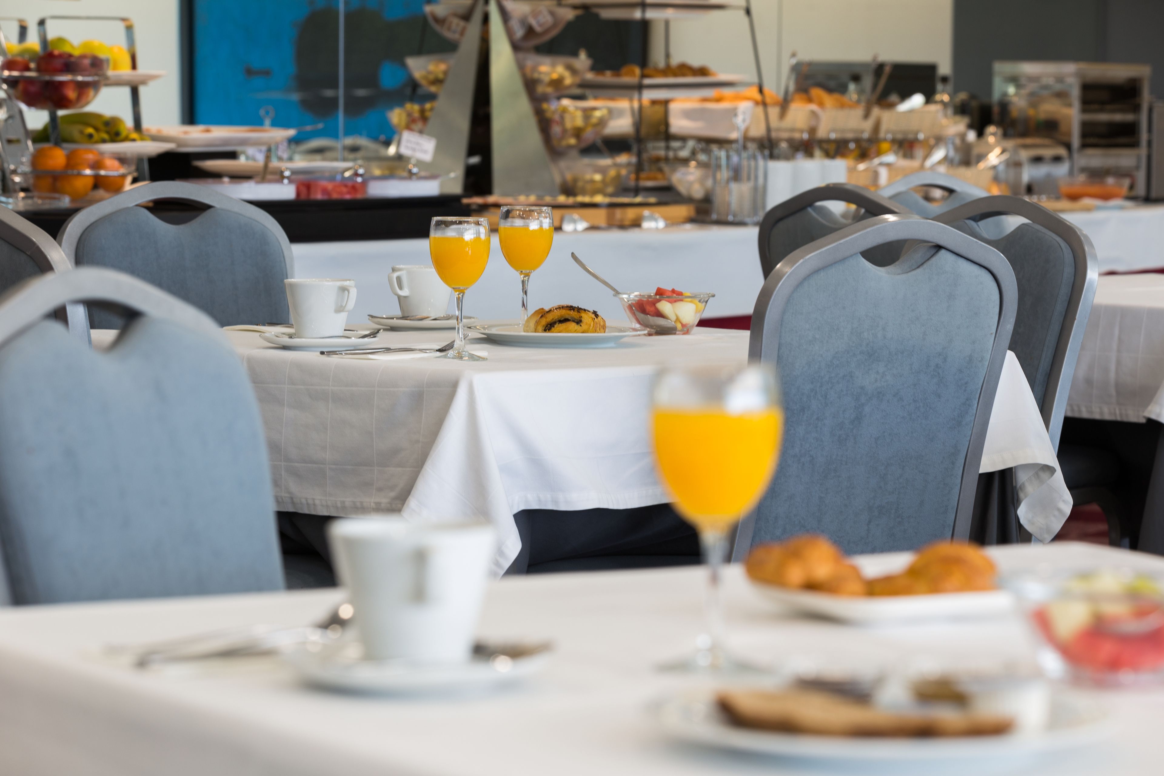 Un bufé de desayuno con diversos alimentos y vasos de jugo de naranja.