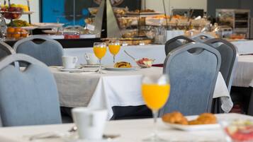 Un bufé de desayuno con diversos alimentos y vasos de jugo de naranja.