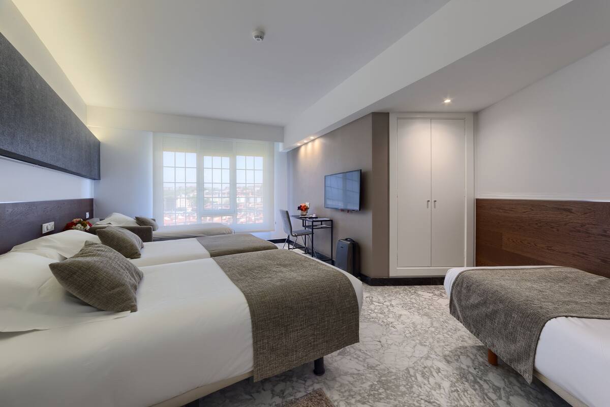 A hotel room with two beds, a TV, a desk, and a wardrobe.