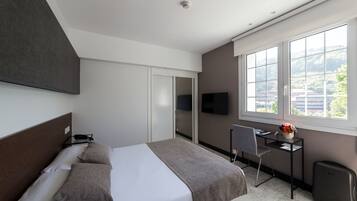 Een moderne hotelkamer met een bed, een bureau en een televisie.