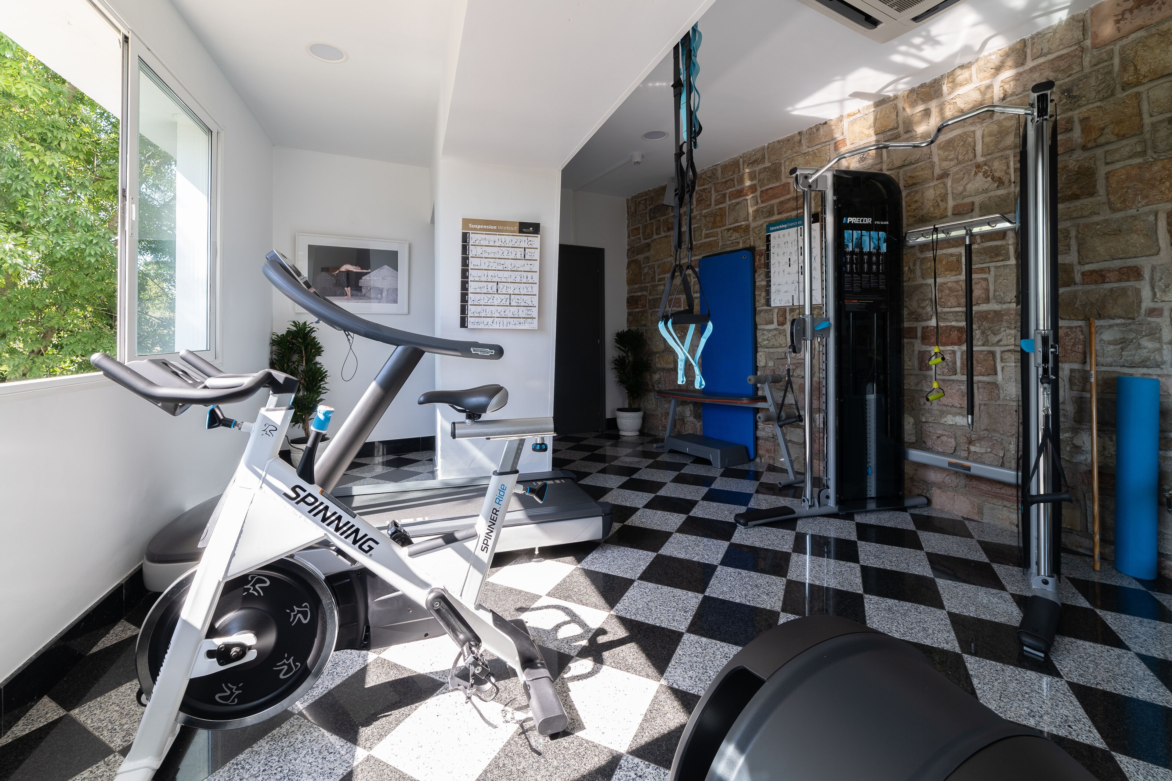 A gym with a spinning bike, a pull-up bar, and a wall calendar.