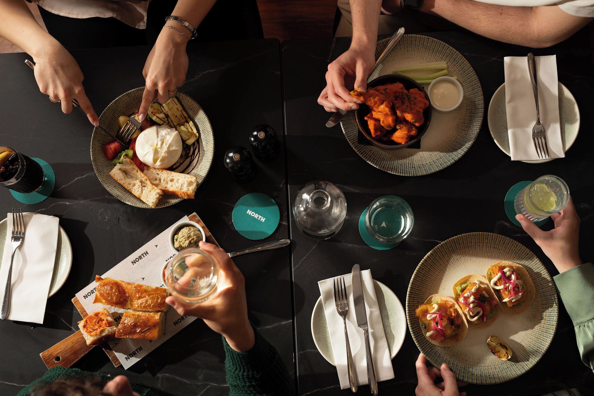 Une table à manger avec des assiettes remplies de nourriture, des couverts et des condiments.