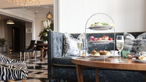 A dining area with a three-tiered dessert stand, a table with food and drinks, a patterned sofa, and a checkered floor. - The Address Cork (Cork)