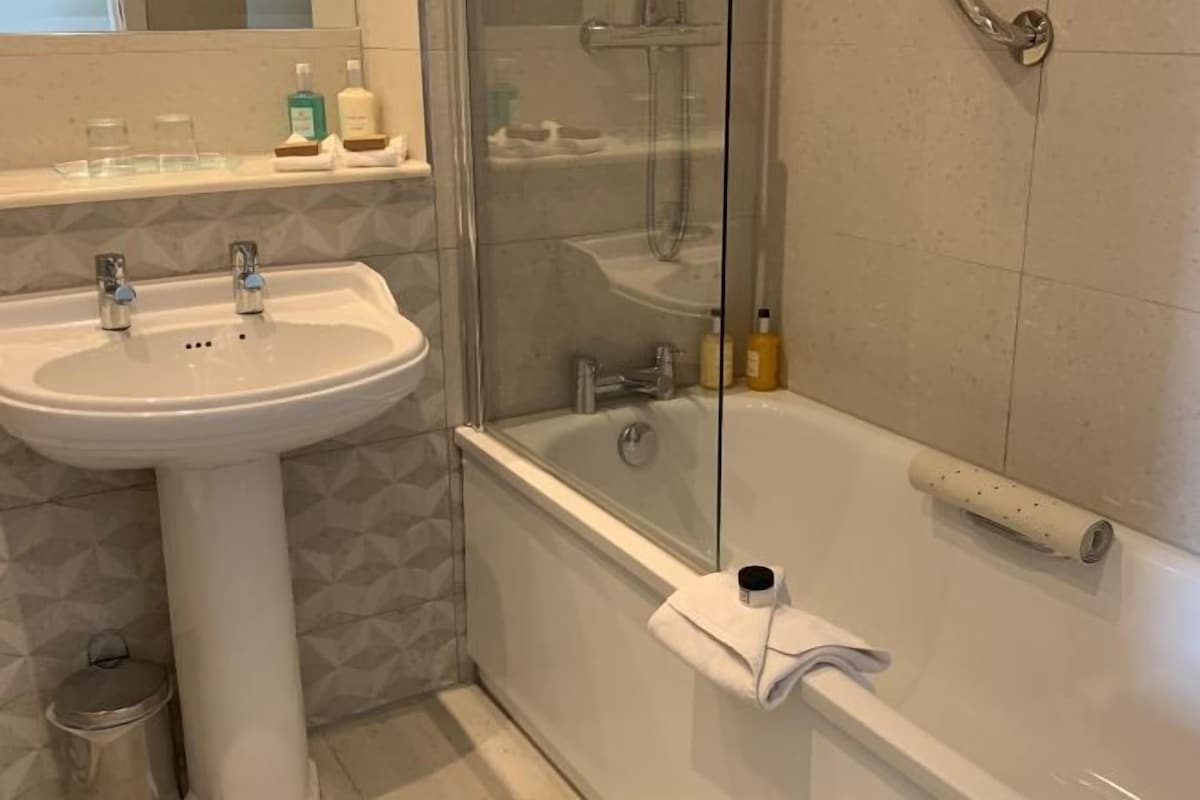 Un baño con lavamanos, espejo y bañera.