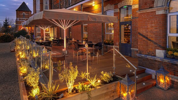 An outdoor patio with wooden decking, seating, and decorative lighting. - The Address Cork (Cork)