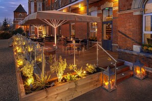 An outdoor patio with wooden decking, seating, and decorative lighting. - The Address Cork (Cork)