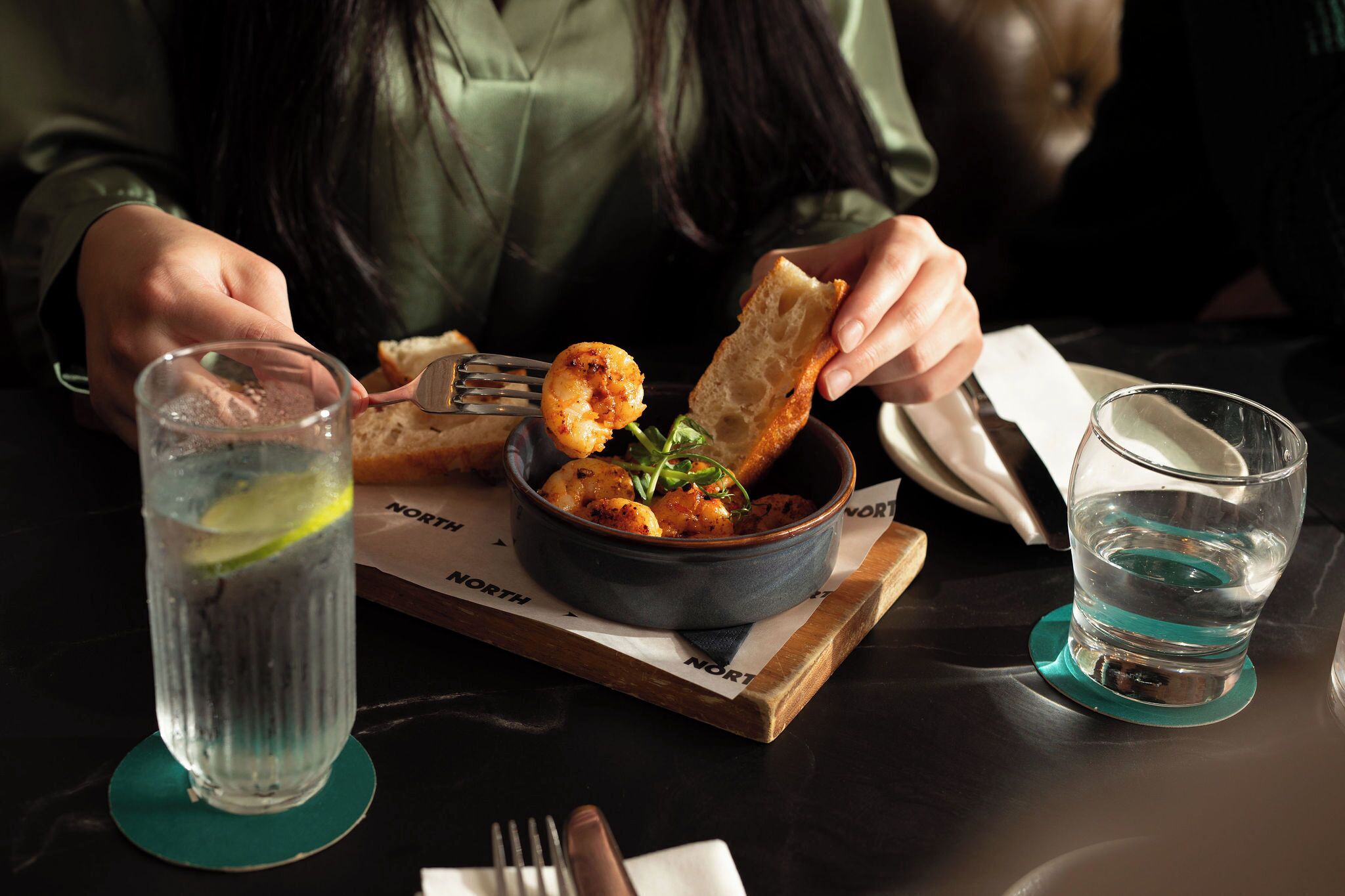 A person dining with a bowl of food, a glass of water, and a menu.