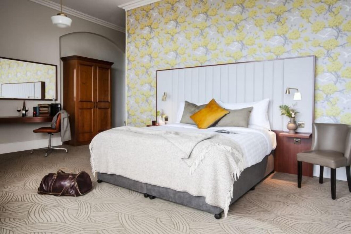 A bedroom with a large bed, a desk, and a chair.